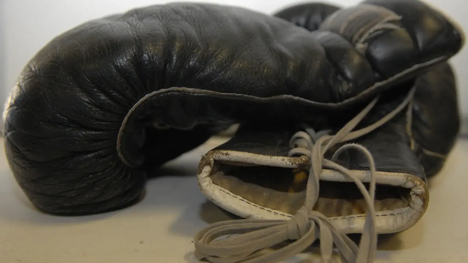 Worn black leather boxing glove with white laces, studio light