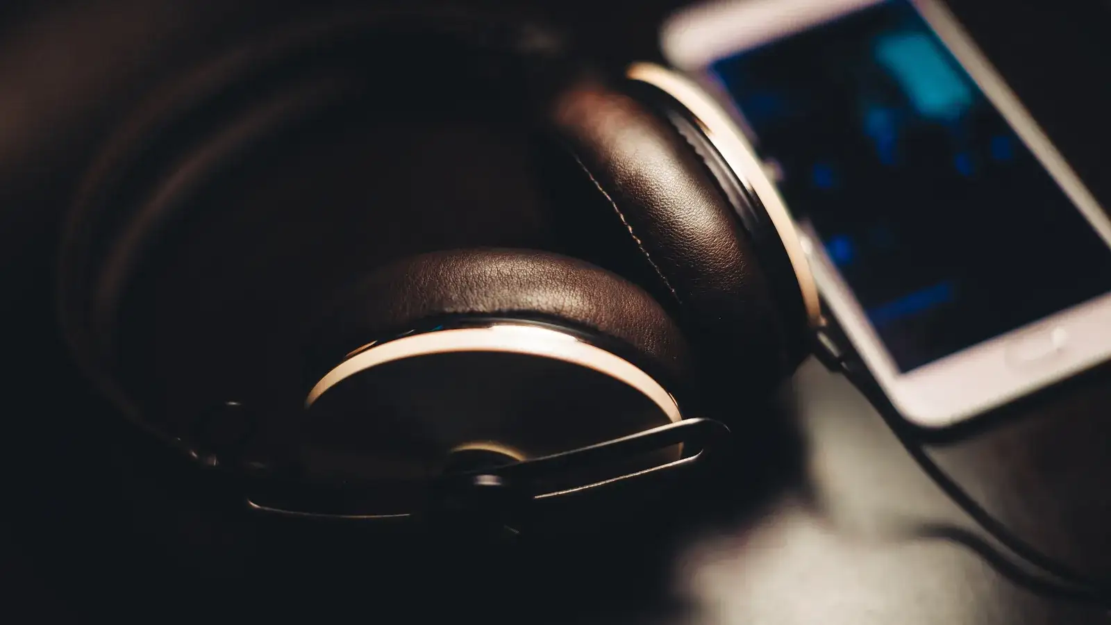 Smartphone with a lit screen beside headphones on a dark surface
